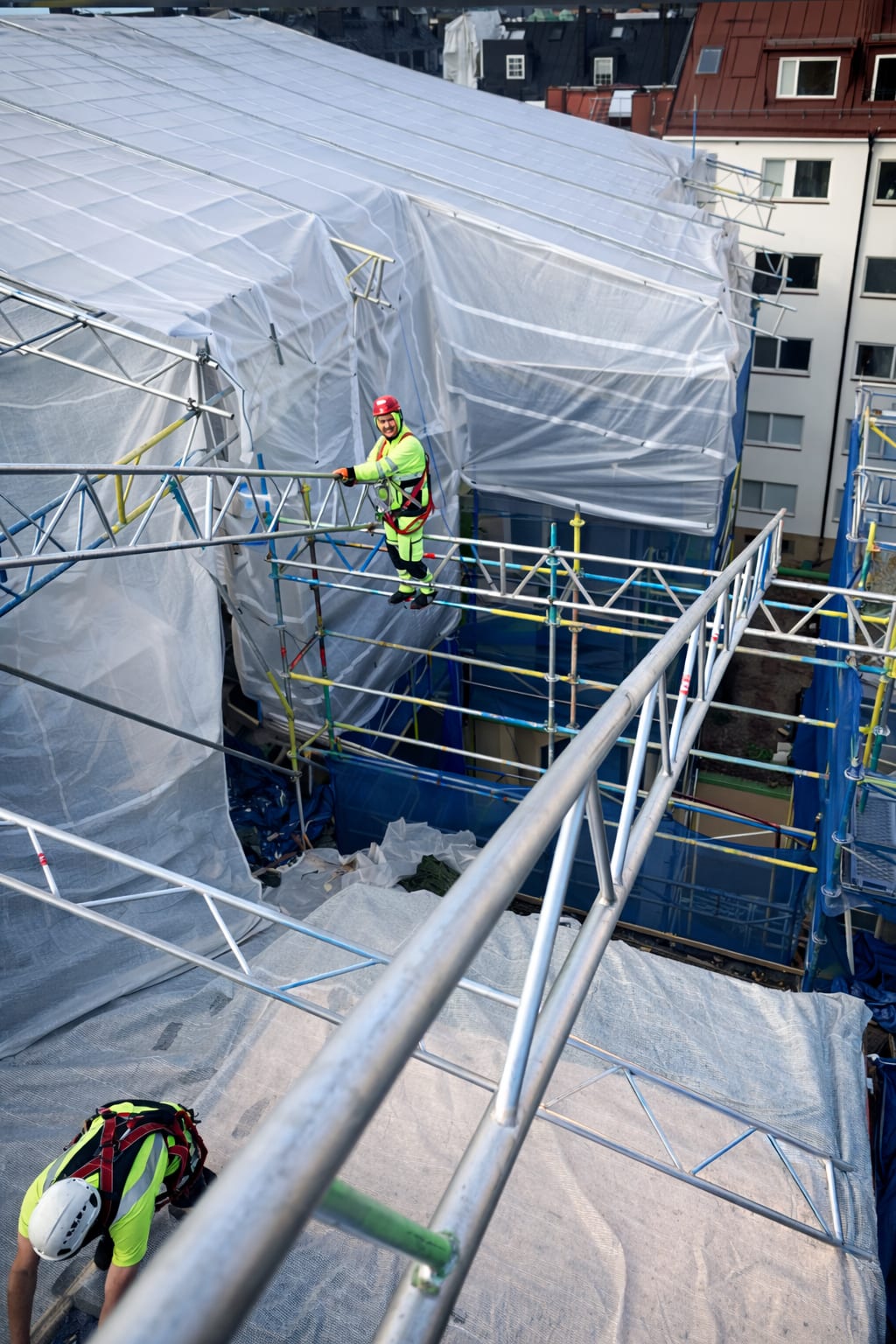 Fully encapsulated scaffold with tarpaulin weather protection shielding facade work from rain and snow
